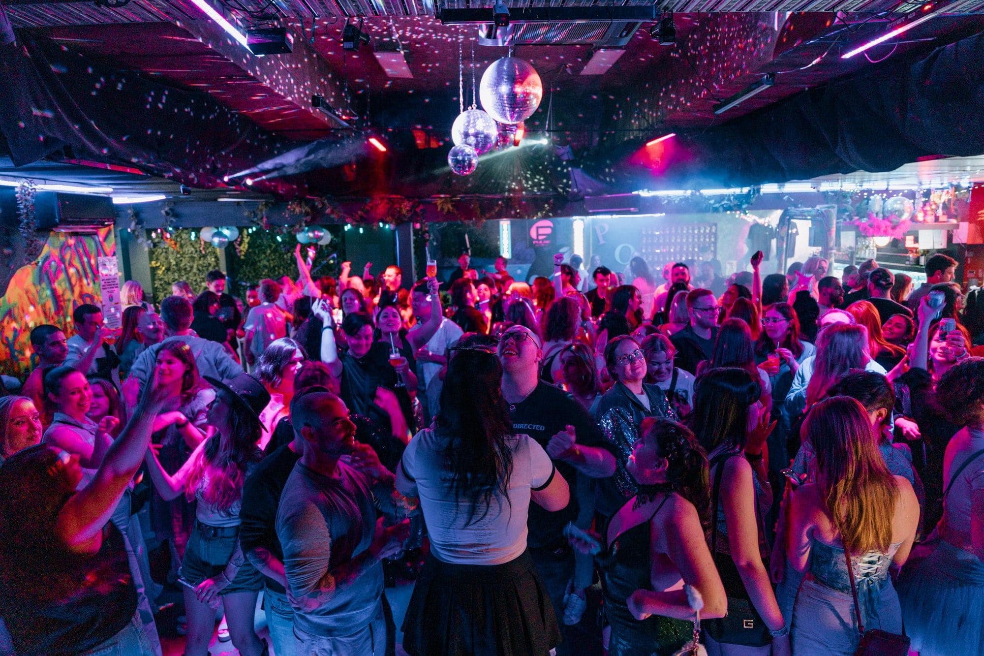 Packed dancefloor at Pride of our Footscray with disco balls and pink and purple lighting